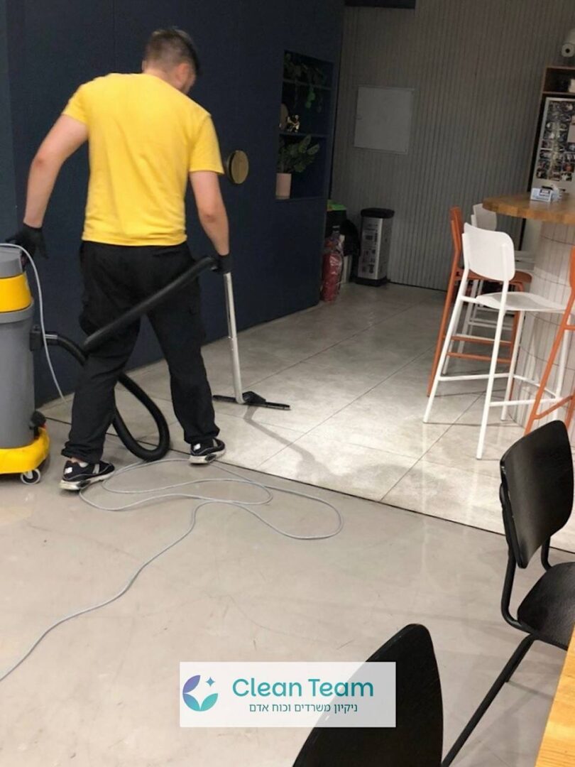 עובד ניקיון שואב רצפת משרד עם שואב אבק תעשייתי