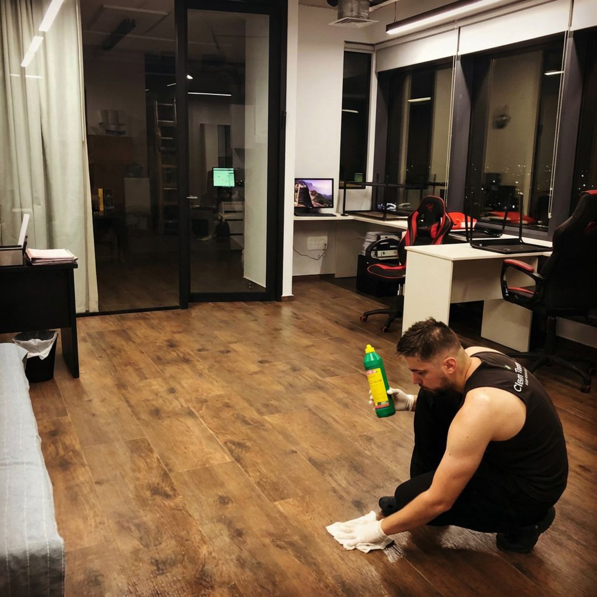 עובד Clean Team מנקה פרקט בעבודת יד במשרד